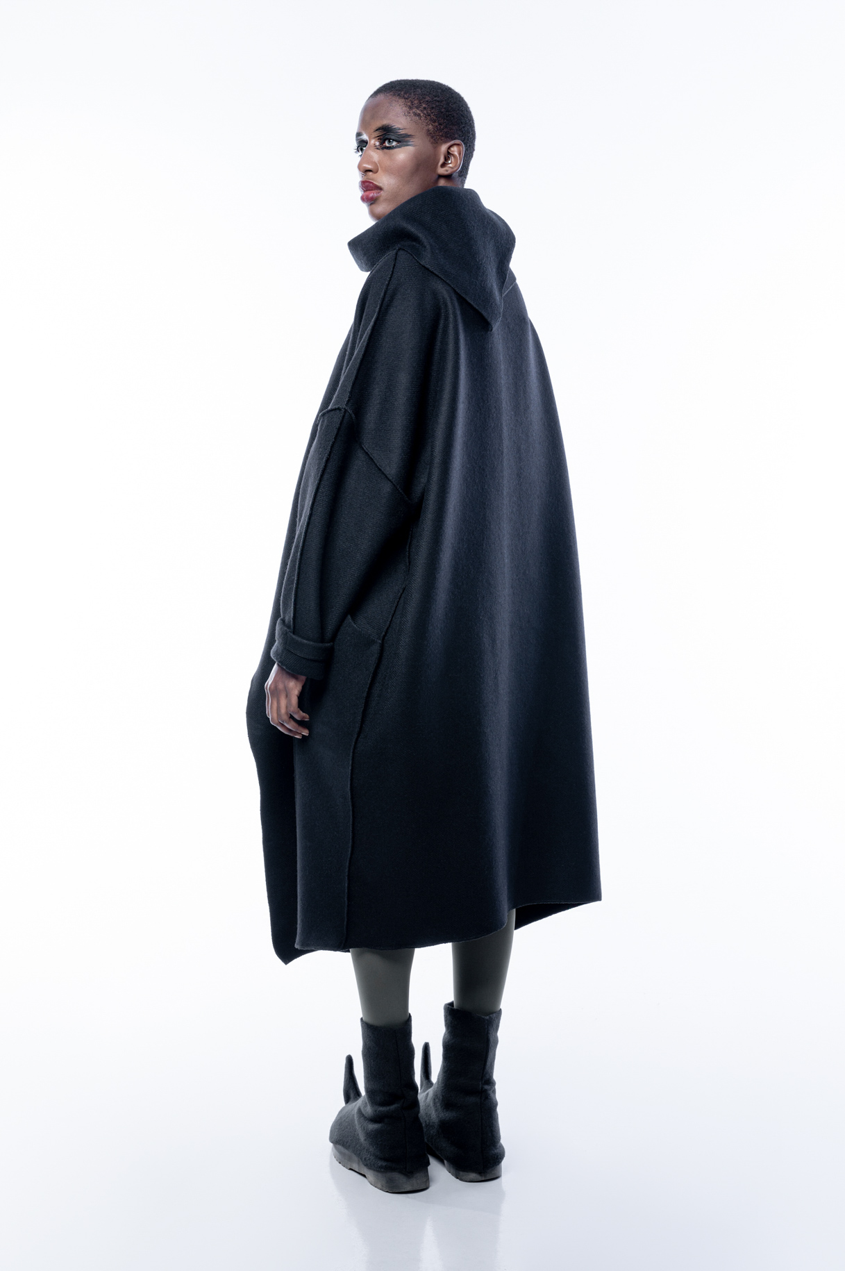 Model from behind in a wide black high-necked coat