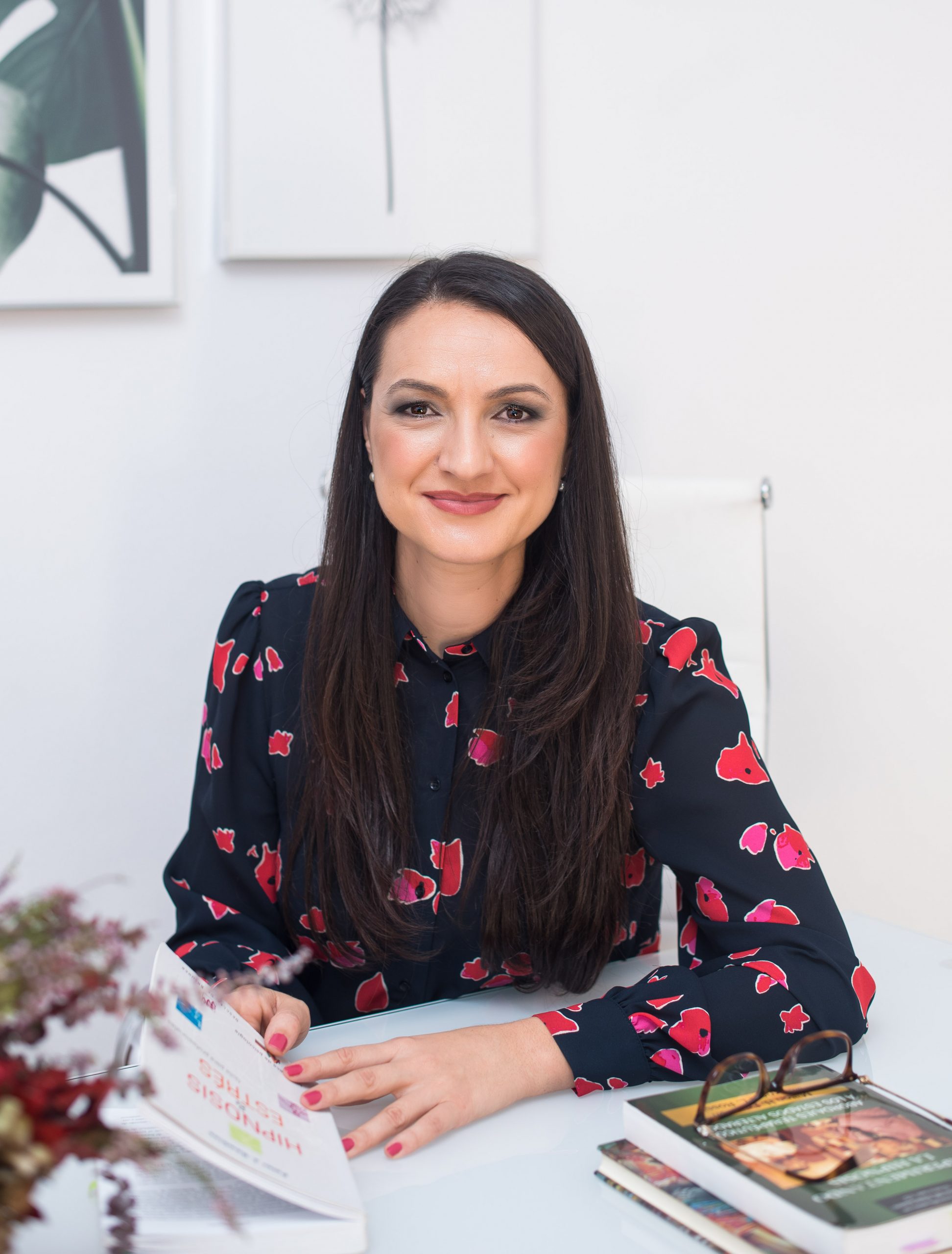 Daniela Constantin sentada a su mesa de trabajo con revistas abiertas