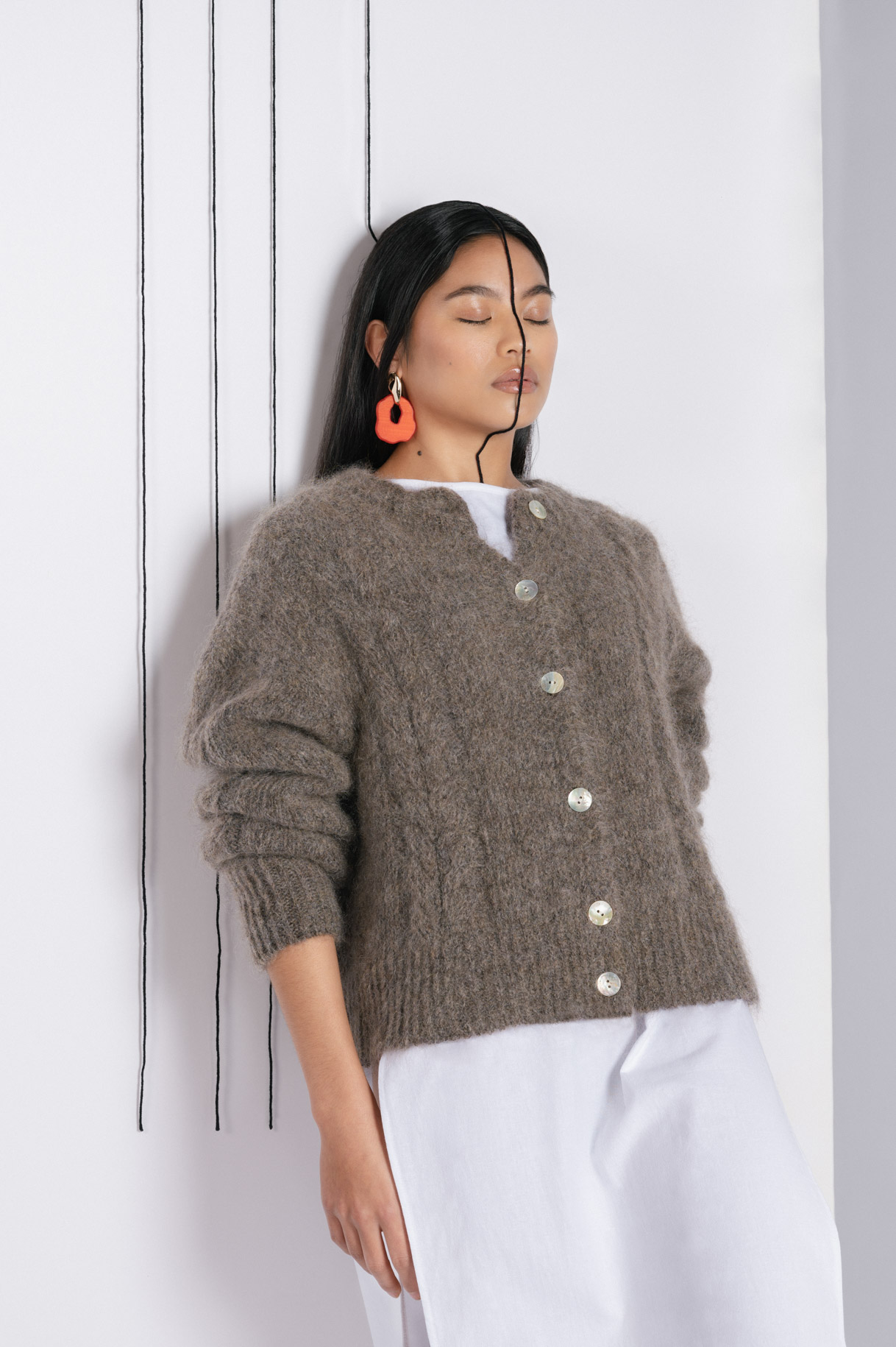 Model leaning against the wall in a brown mohair cardigan